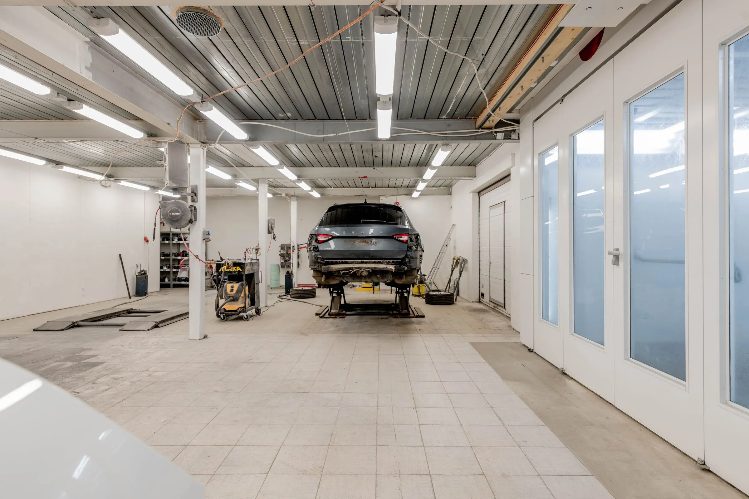 A vehicle raised on a lift in an empty, brightly lit service bay